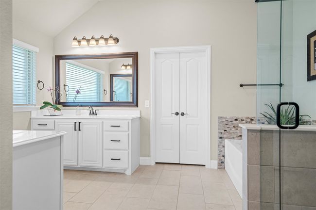 Bathroom with two vanities, tile patterned flooring, a garden tub, and vaulted ceiling | Image 22