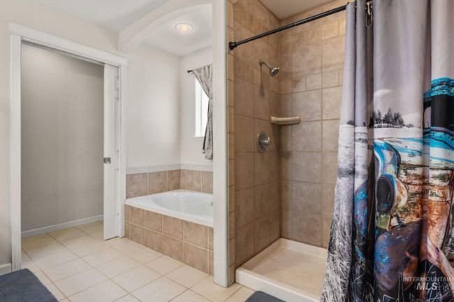 Bathroom featuring tiled flooring, tiled shower, and a garden tub, dual vanities | Image 24
