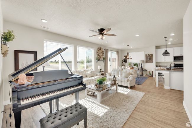 Living room featuring a ceiling fan, light wood-style floors, a textured ceiling, recessed lighting, and baseboards | Image 7