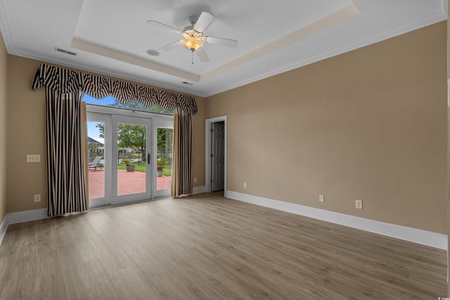 Spare room with a tray ceiling, light wood-style flooring, ceiling fan, and crown molding | Image 20