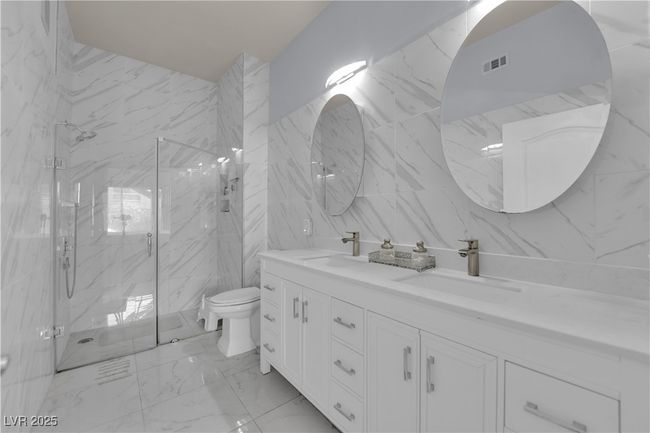 Bathroom with double vanity, marble look tiles, a marble finish shower, and tile walls | Image 30