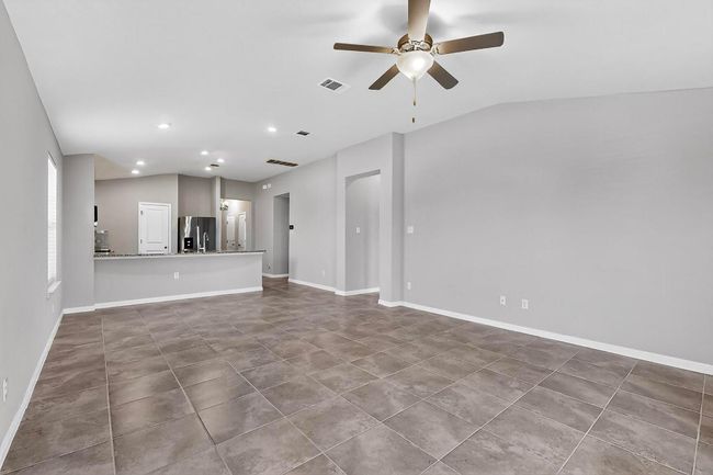 Unfurnished living room with lofted ceiling, a ceiling fan, tile patterned floors, and recessed lighting | Image 9
