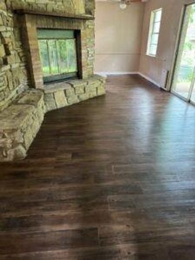 Unfurnished living room with a fireplace, dark wood-type flooring, and a healthy amount of sunlight | Image 2