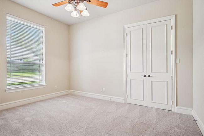Secondary bedroom with new carpet, walk-in closet and a ceiling fan. | Image 25