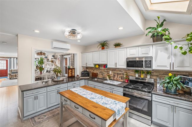 Kitchen with stainless steel appliances, a sink, a wall unit AC, tasteful backsplash, and recessed lighting | Image 12