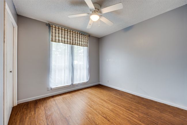 Empty room featuring wood finished floors, baseboards, ceiling fan, and a textured ceiling | Image 10