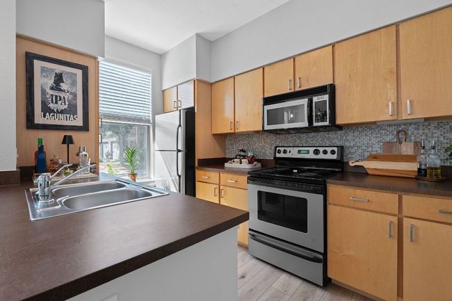 Kitchen with electric stove, freestanding refrigerator, dark countertops, and backsplash | Image 10