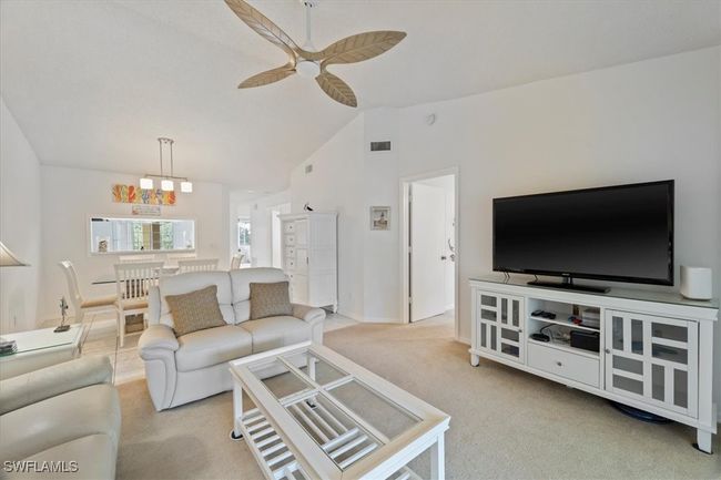 Carpeted living room featuring visible vents, ceiling fan with notable chandelier, baseboards, and lofted ceiling | Image 9