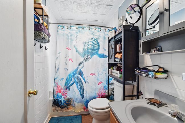 Full bathroom featuring an ornate ceiling, shower / tub combo, toilet, vanity, and wood finished floors | Image 9