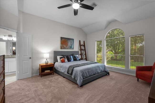 This spacious primary bedroom features a large arched window offering plenty of natural light and views of the lake. | Image 17