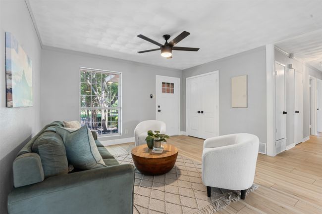 Living room with ceiling fan, light wood-style floors, and crown molding | Image 9