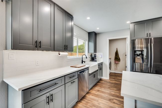 Kitchen with appliances with stainless steel finishes, a sink, tasteful backsplash, light wood-style flooring, and light stone counters | Image 11