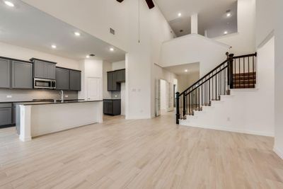 Kitchen with ceiling fan, gray cabinetry, a center island with sink, light hardwood / wood-style flooring, and a high ceiling | Image 2