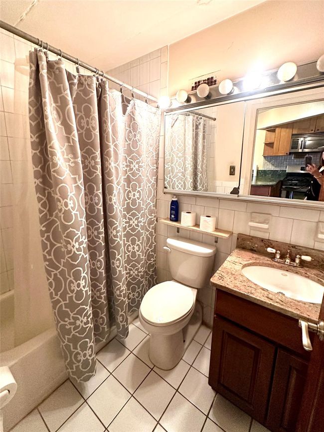 Bathroom with shower / bath combo with shower curtain, tile patterned flooring, vanity, and tasteful backsplash | Image 6
