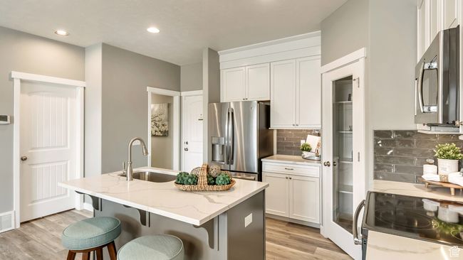 Kitchen featuring white cabinetry, a sink, appliances with stainless steel finishes, and light wood-type flooring | Image 4