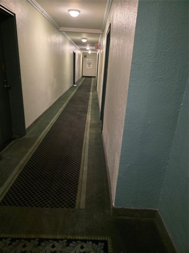 Corridor with a textured wall, ornamental molding, and dark colored carpet | Image 16
