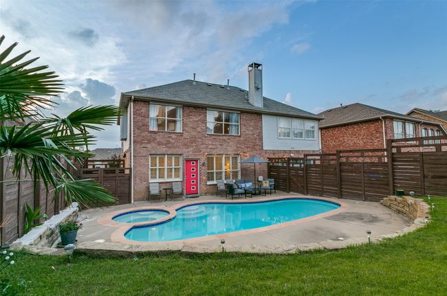 Rear view of house with a chimney, brick siding, a fenced backyard, a patio, and a pool with connected hot tub | Image 24