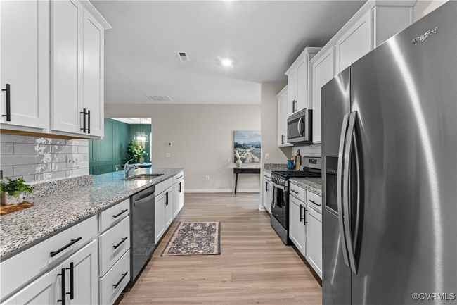 Kitchen with appliances with stainless steel finishes, white cabinetry, tasteful backsplash, and light wood finished floors | Image 13