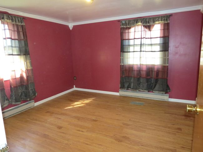 unfurnished room featuring visible vents, a baseboard heating unit, wood finished floors, crown molding, and baseboards | Image 9