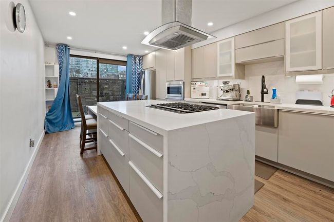 Kitchen featuring stainless steel appliances, island exhaust hood, a sink, light wood-style floors, and recessed lighting | Image 5