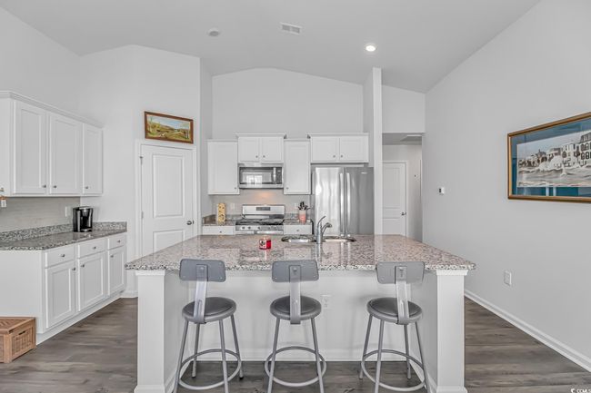 Kitchen featuring sink, a kitchen island with sink, stainless steel appliances, light stone countertops, and white cabinets | Image 4