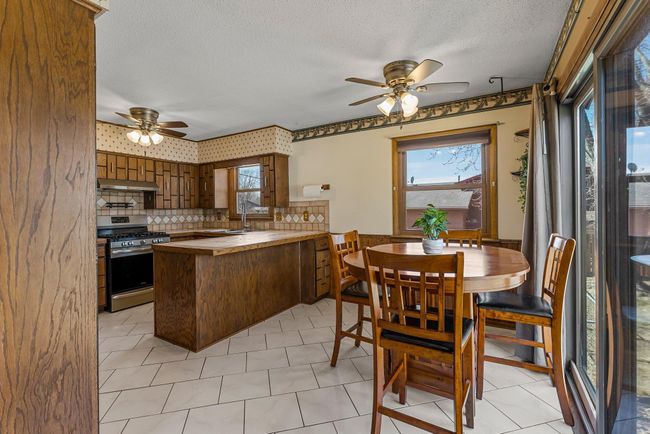 The dining room, connected to the kitchen, includes classic wood wainscoting, ceramic tile flooring, and a window that brings in natural light. | Image 8