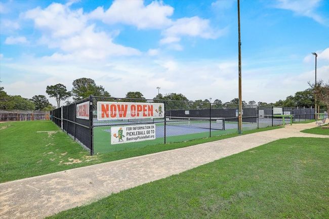 View of tennis court with a yard and fence | Image 14