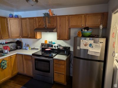 Kitchen with a textured ceiling, stainless steel appliances, and dark hardwood / wood-style floors | Image 3