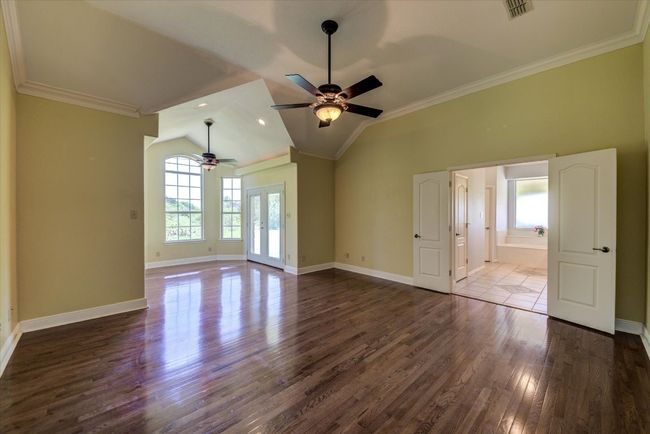 This private and expansive primary bedroom offers a separate sitting area with French doors leading to the covered patio, and double doors leading to the en-suite primary bathroom. | Image 13