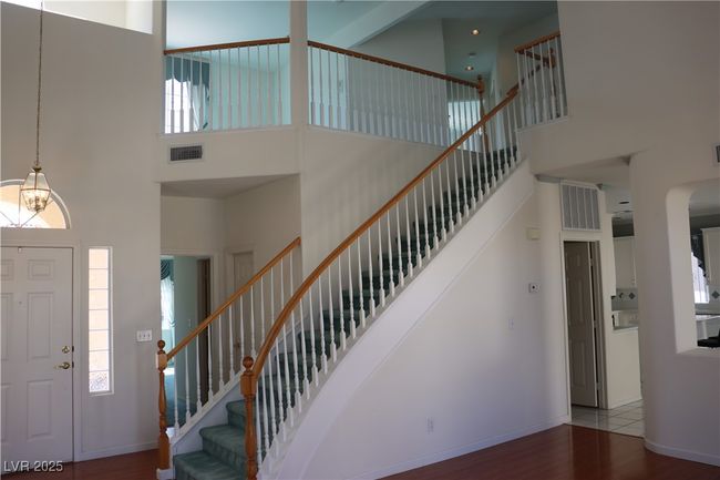 Foyer entrance with a towering ceiling, wood finished floors, a chandelier, stairway, and arched walkways | Image 24