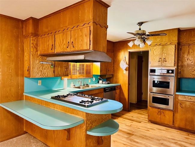 Kitchen with under cabinet range hood, brown cabinets, and appliances with stainless steel finishes | Image 5