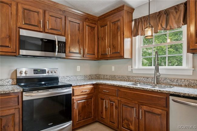 Kitchen with appliances with stainless steel finishes, a sink, and brown cabinetry | Image 14