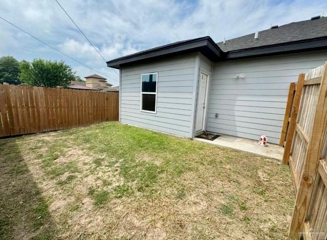 Rear view of property featuring a fenced backyard, a yard, and roof with shingles | Image 11