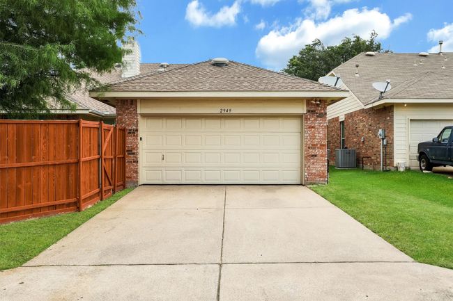 View of front facade with brick siding, a shingled roof, concrete driveway, and central AC unit | Image 32