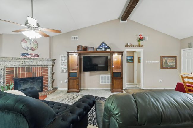 Living room with vaulted ceiling with beams, visible vents, carpet floors, and ceiling fan | Image 11