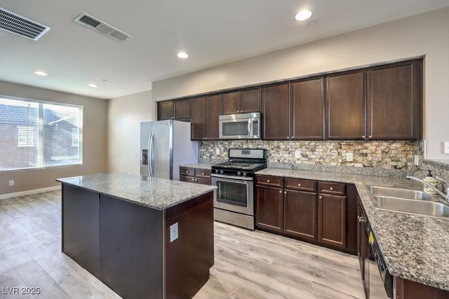 Kitchen featuring a center island, visible vents, a sink, and stainless steel appliances | Image 6