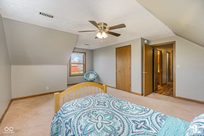 bedroom with a textured ceiling, visible vents, baseboards, light carpet, and lofted ceiling | Image 20