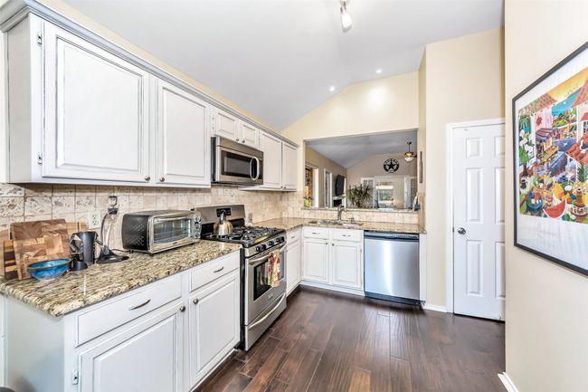 Kitchen featuring stainless steel appliances, a sink, lofted ceiling, tasteful backsplash, and dark wood-style flooring | Image 6