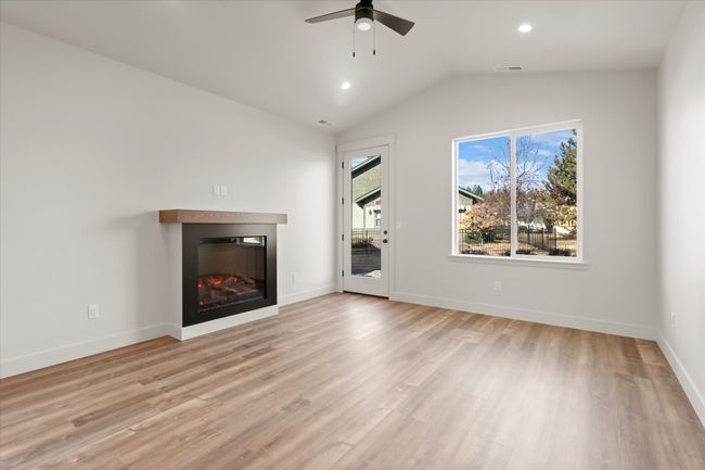 Unfurnished living room featuring visible vents, light wood-style flooring, a ceiling fan, and vaulted ceiling | Image 11