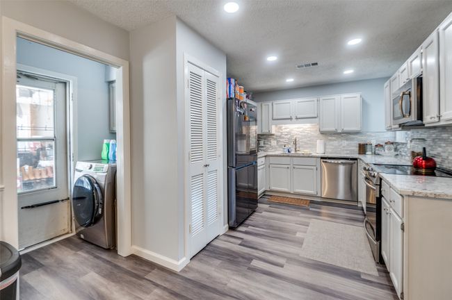 Kitchen featuring stainless steel appliances, washer / dryer, light wood finished floors, tasteful backsplash, and recessed lighting | Image 6