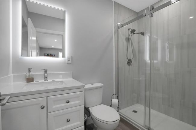 Bathroom featuring vanity, toilet, and a shower with door | Image 30