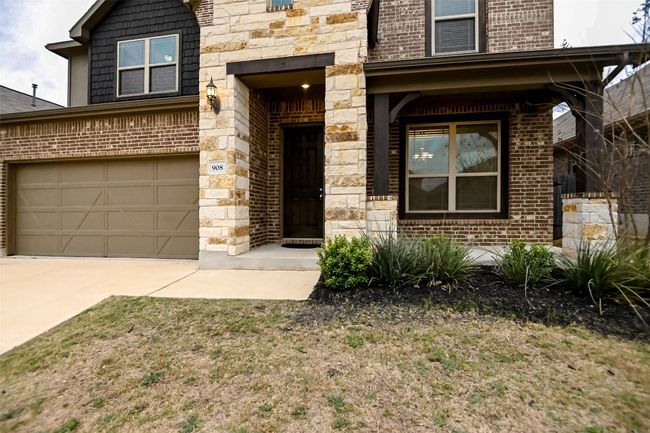 View of front facade with driveway, stone siding, an attached garage, and brick siding | Image 5