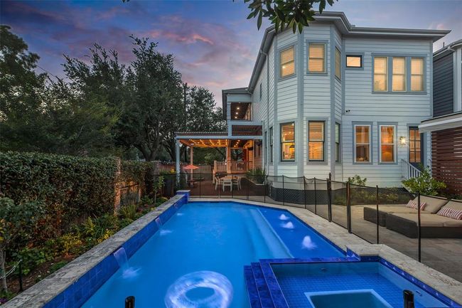 Look at this fabulous backyard featuring a pool and hot tub. The outdoor area includes a covered patio for dining and relaxation, surrounded by lush greenery, creating a perfect space for entertaining. | Image 33