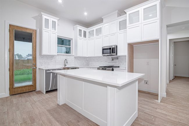 Kitchen featuring appliances with stainless steel finishes, tasteful backsplash, light wood-style flooring, white cabinets, and recessed lighting | Image 8