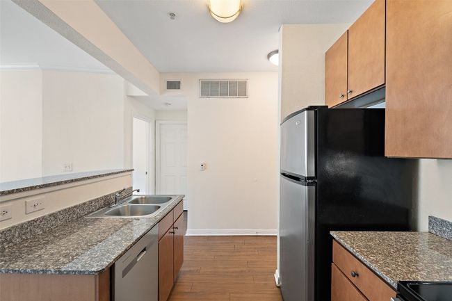 Kitchen featuring dark wood-type flooring, brown cabinetry, and appliances with stainless steel finishes | Image 4
