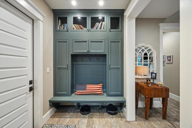 Located just off the two-car garage, this custom-designed drop zone offers seamless access for unloading and organizing as you come in from your vehicle. With its practical bench, hooks, ample storage, and convenient electrical outlets, it’s the perfect space to keep everything tidy and easily accessible. | Image 26