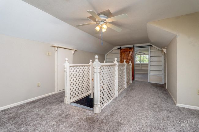 Additional living space featuring ceiling fan, lofted ceiling, a barn door, and carpet | Image 24