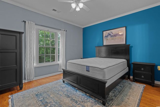Bedroom featuring ornamental molding, baseboards, wood finished floors, and a ceiling fan | Image 22