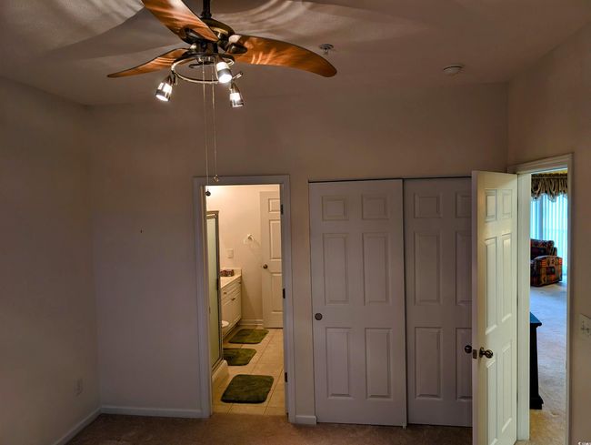 Bedroom with a closet, baseboards, ceiling fan, light carpet, and ensuite bath | Image 12