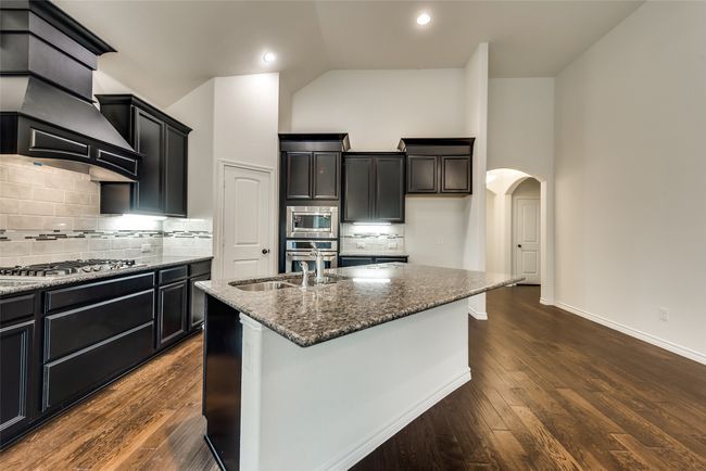 Kitchen featuring appliances with stainless steel finishes, high vaulted ceiling, arched walkways, dark stone counters, and dark wood-type flooring | Image 8
